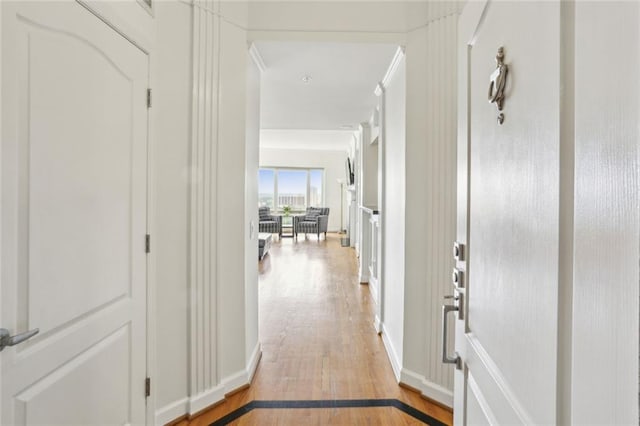 corridor featuring light wood-style flooring and baseboards