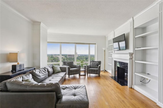 living area with crown molding, a textured ceiling, wood finished floors, and a premium fireplace