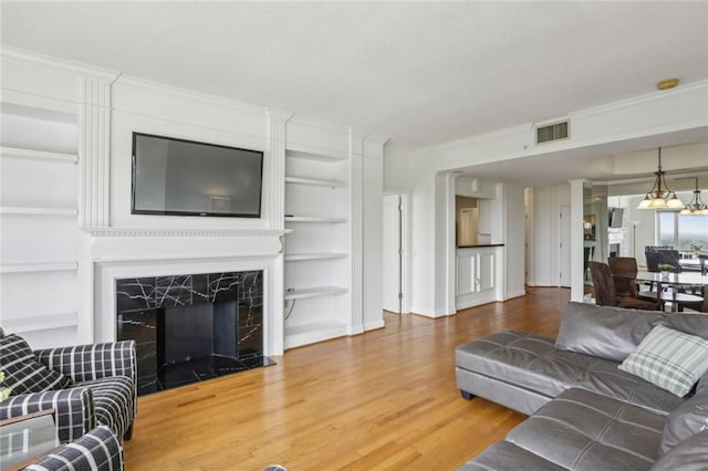 living area featuring crown molding, visible vents, built in features, and wood finished floors