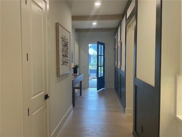 hall featuring beamed ceiling and light hardwood / wood-style flooring