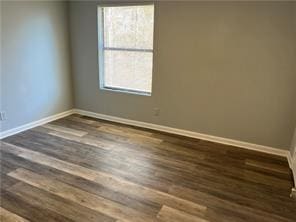 unfurnished room featuring dark hardwood / wood-style floors and plenty of natural light