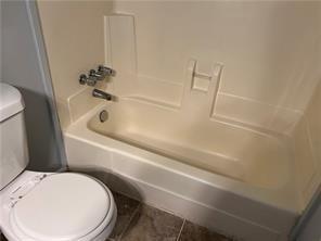 bathroom with tile patterned floors, shower / washtub combination, and toilet