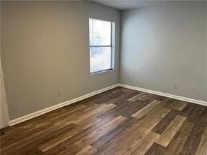 empty room with dark hardwood / wood-style flooring