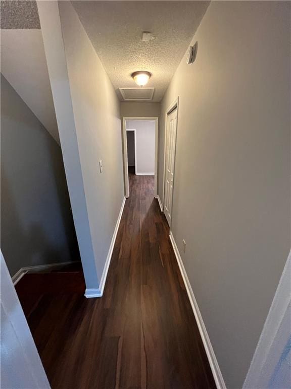 hallway featuring a textured ceiling and dark hardwood / wood-style floors