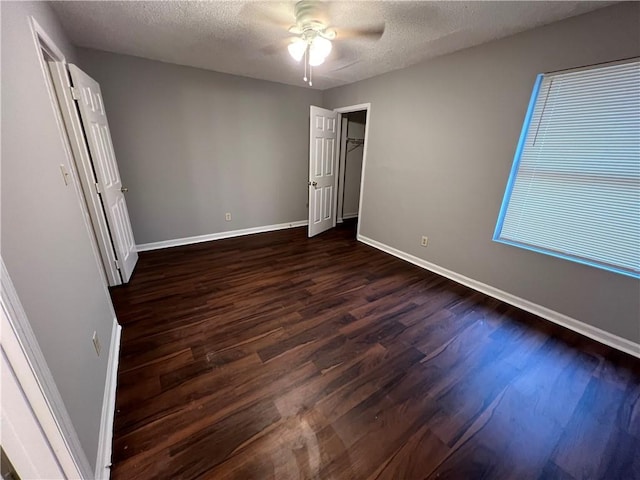 unfurnished bedroom featuring a textured ceiling, ceiling fan, and dark wood-type flooring