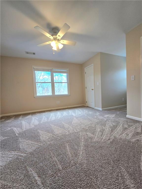 spare room featuring a ceiling fan, carpet flooring, visible vents, and baseboards