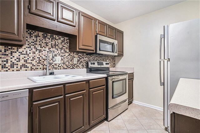 kitchen featuring sink, light tile patterned floors, appliances with stainless steel finishes, tasteful backsplash, and dark brown cabinetry