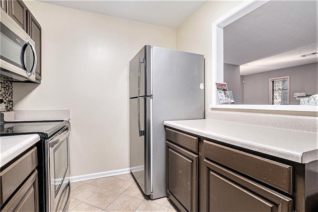 kitchen featuring dark brown cabinets, light tile patterned floors, and stainless steel appliances