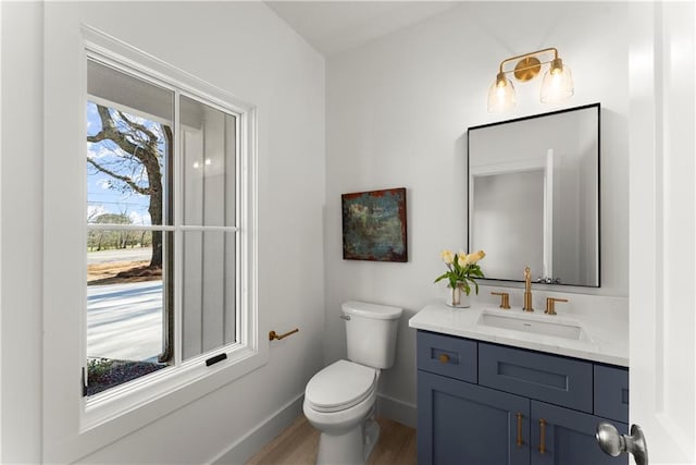 bathroom featuring vanity, toilet, wood finished floors, and baseboards