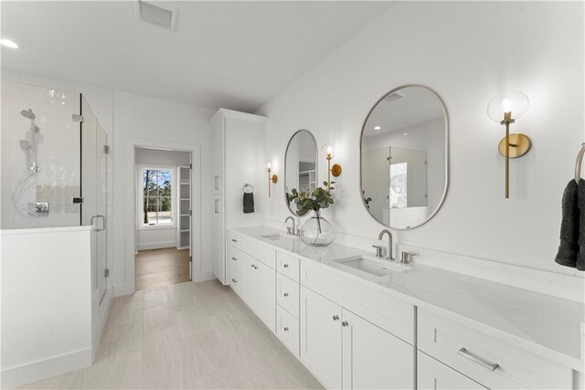 bathroom with a sink, visible vents, and a stall shower