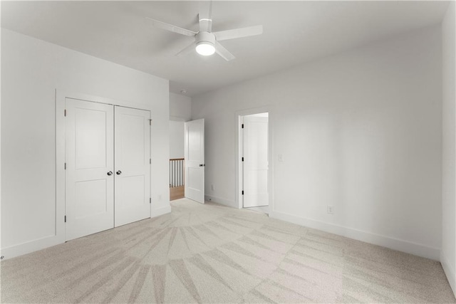 unfurnished bedroom with a ceiling fan, light colored carpet, a closet, and baseboards