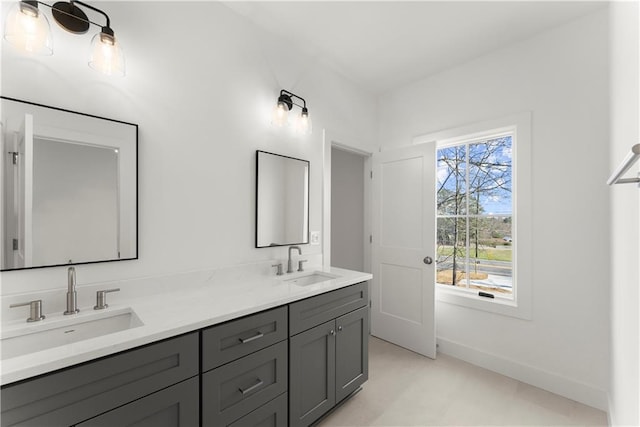 full bath featuring double vanity, baseboards, and a sink