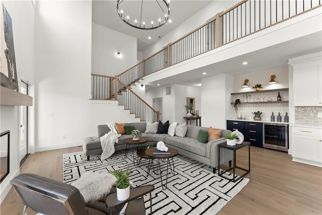 living room with beverage cooler, a dry bar, light wood finished floors, and a towering ceiling