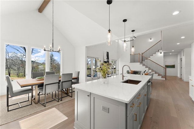 kitchen with light wood-type flooring, gray cabinetry, a sink, stainless steel dishwasher, and open floor plan