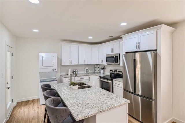 kitchen featuring light hardwood / wood-style floors, sink, stainless steel appliances, and an island with sink