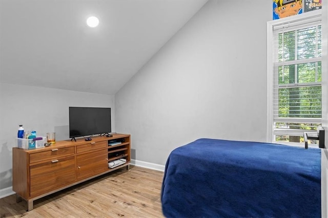 bedroom featuring light wood-type flooring, baseboards, and vaulted ceiling