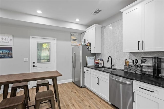 kitchen featuring visible vents, a sink, appliances with stainless steel finishes, tasteful backsplash, and light wood-type flooring