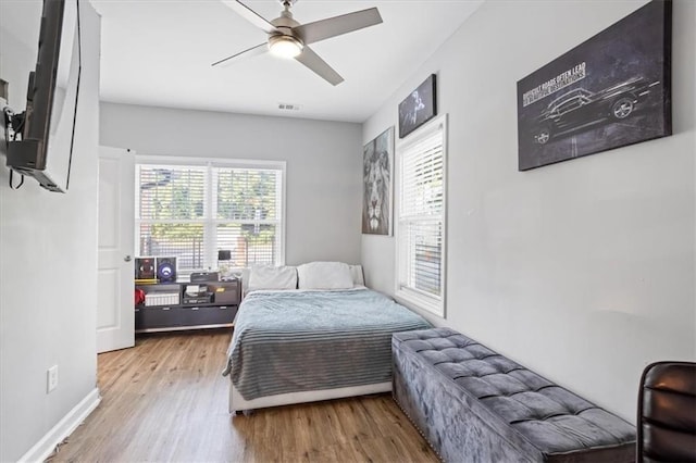 bedroom featuring baseboards, wood finished floors, visible vents, and ceiling fan