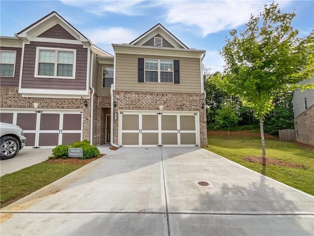 view of property featuring brick siding, concrete driveway, a front yard, and a garage
