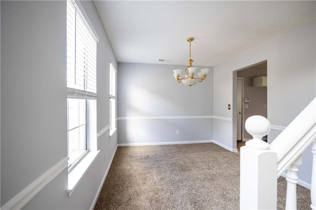 spare room with a wall unit AC, carpet floors, and an inviting chandelier