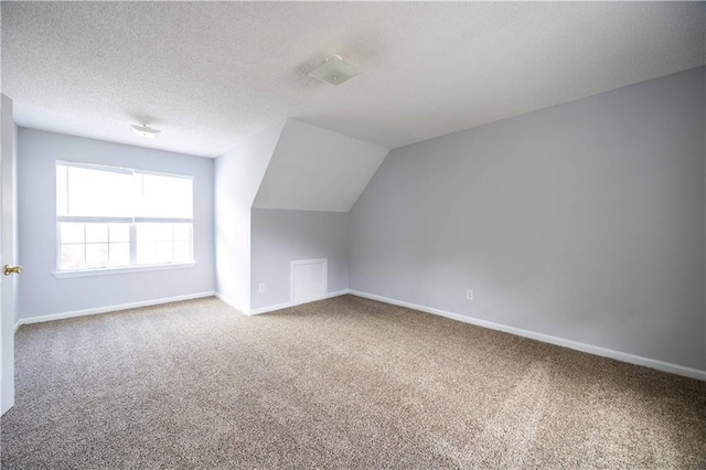 bonus room with carpet floors, lofted ceiling, and a textured ceiling