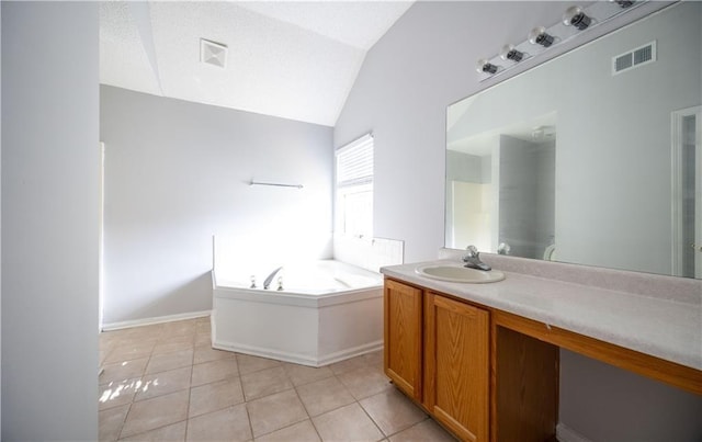 bathroom with tile patterned flooring, a bathtub, vanity, and vaulted ceiling