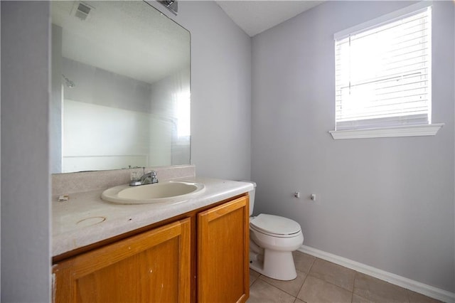 bathroom with toilet, vanity, and tile patterned flooring