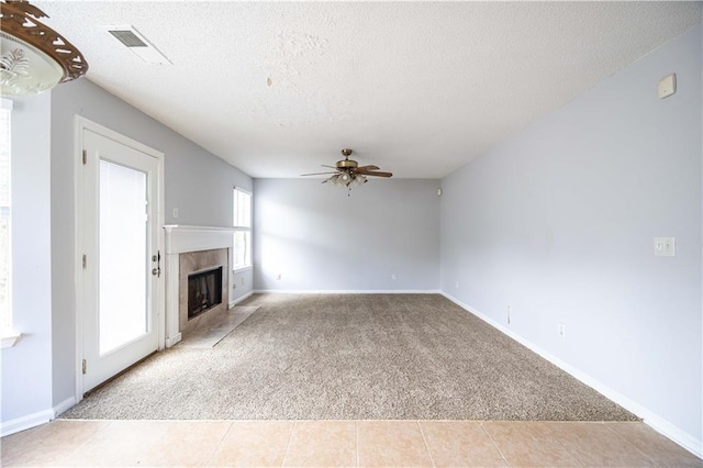 unfurnished living room featuring a textured ceiling, light colored carpet, ceiling fan, and a fireplace