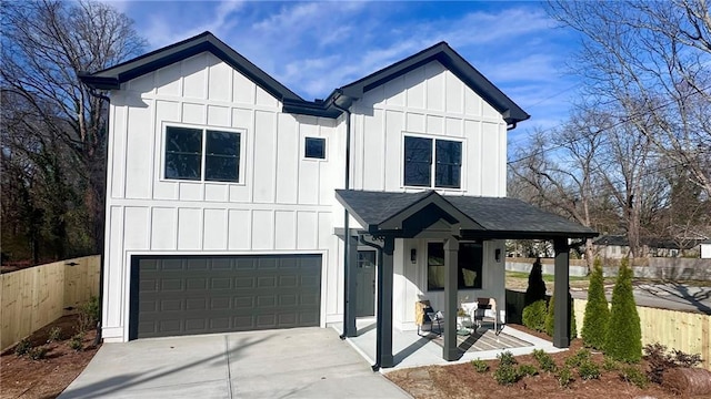 modern inspired farmhouse with a garage, a shingled roof, fence, and board and batten siding