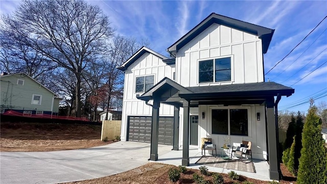 modern farmhouse with board and batten siding, concrete driveway, a porch, and an attached garage