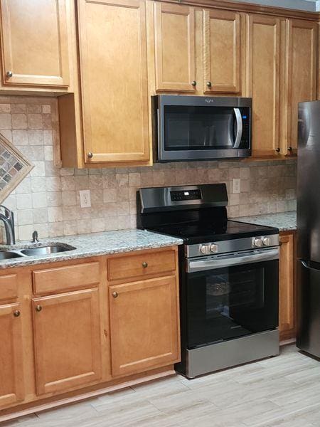 5449 Festival Ave, Fairburn, GA 30213 - kitchen featuring stainless steel appliances, a sink, tasteful backsplash, and light stone countertops