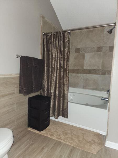 5449 Festival Ave, Fairburn, GA 30213 - bathroom featuring shower / bath combination with curtain, wood finished floors, vaulted ceiling, tile walls, and toilet