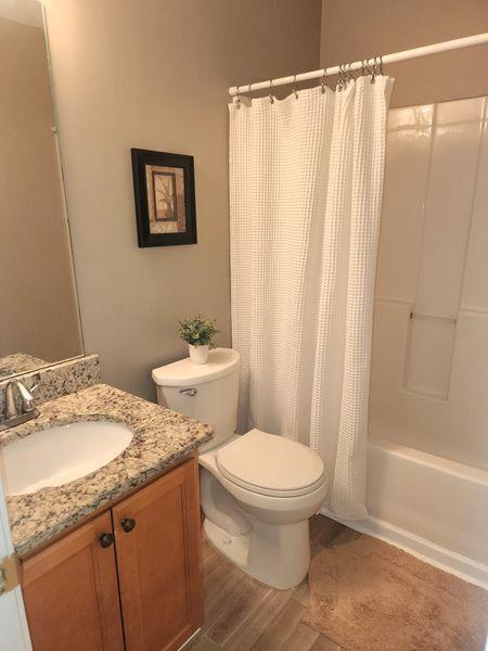 5449 Festival Ave, Fairburn, GA 30213 - full bathroom with toilet, wood finished floors, vanity, and shower / bath combo with shower curtain
