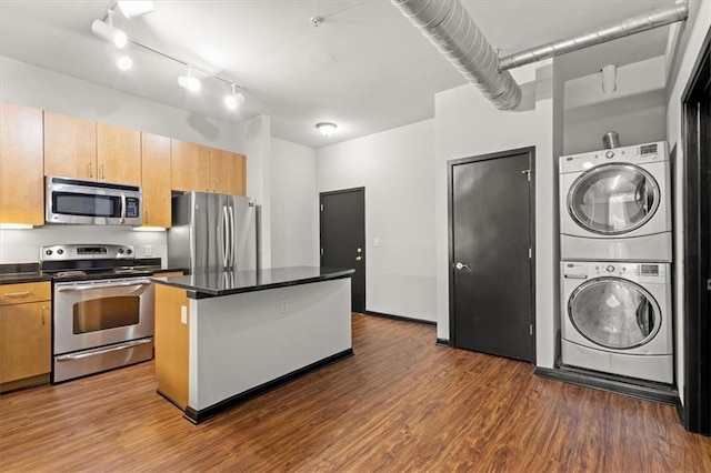 kitchen with stacked washer and dryer, a center island, stainless steel appliances, and dark hardwood / wood-style flooring