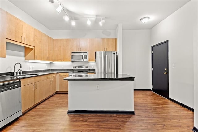 kitchen featuring sink, a center island, stainless steel appliances, light brown cabinets, and light wood-type flooring