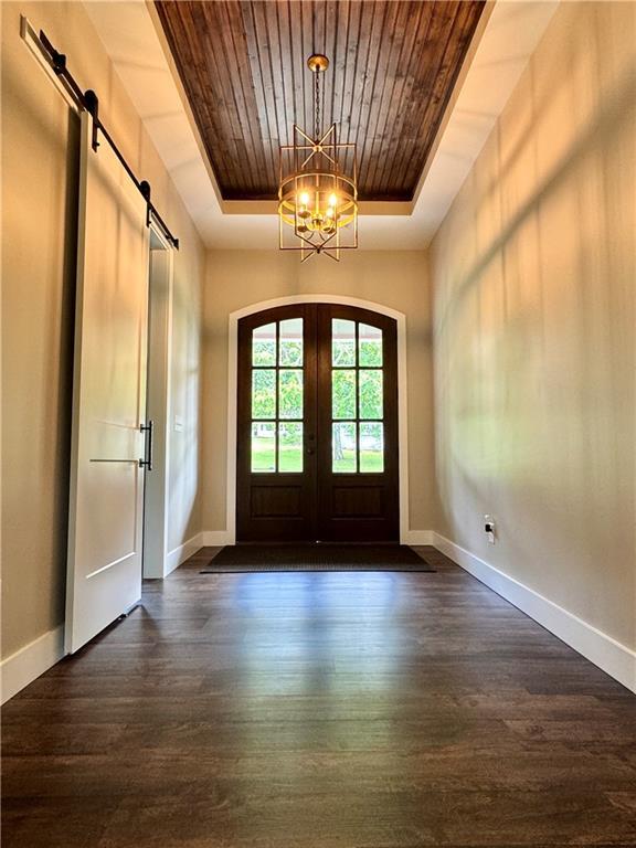 112 Three Oaks Dr SE, Calhoun, GA 30701 - foyer entrance featuring a raised ceiling, wooden ceiling, a chandelier, a barn door, and dark wood-style floors