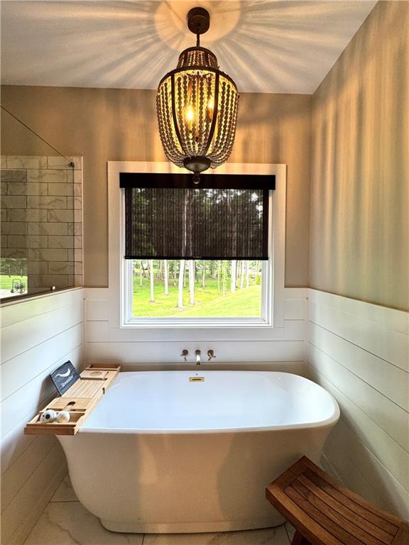 112 Three Oaks Dr SE, Calhoun, GA 30701 - full bath featuring a soaking tub, wooden walls, and marble look tile flooring
