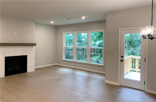 7206 Grand Reunion Dr, Hoschton, GA 30548 - unfurnished living room with wood finished floors, healthy amount of natural light, a chandelier, a fireplace, and recessed lighting