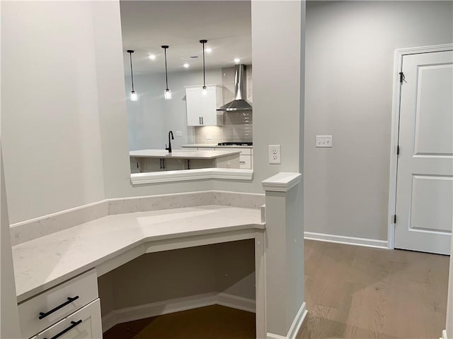 7206 Grand Reunion Dr, Hoschton, GA 30548 - kitchen with wall chimney exhaust hood, white cabinets, pendant lighting, light wood finished floors, and stovetop