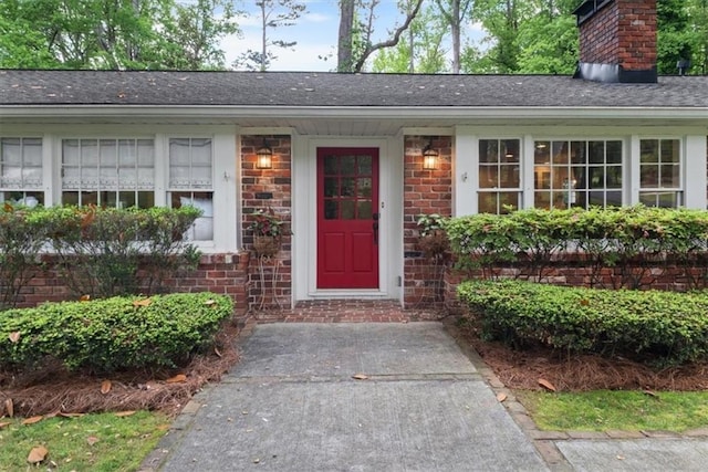 302 Chinquapin Dr SW, Marietta, GA 30064 - view of exterior entry featuring a chimney, brick siding, and a shingled roof