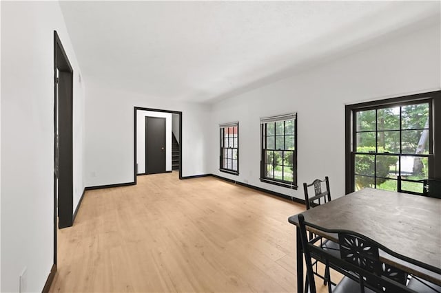 dining space with light wood-type flooring, baseboards, and stairway