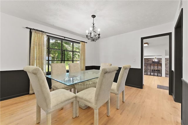 dining space with light wood-type flooring, a chandelier, and a textured ceiling