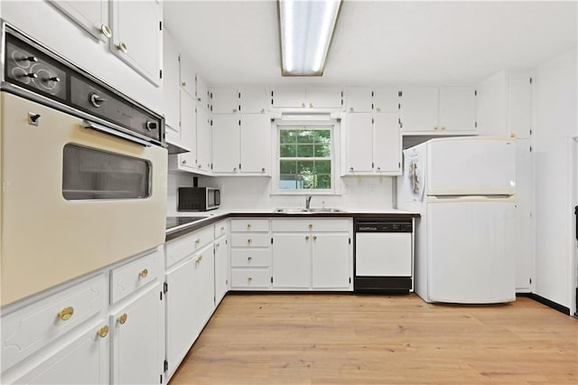 kitchen with white appliances, tasteful backsplash, light wood-type flooring, white cabinetry, and a sink