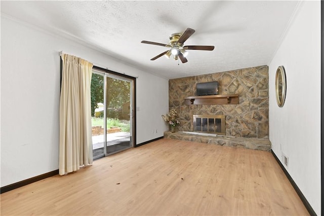 unfurnished living room featuring a fireplace, a textured ceiling, baseboards, and wood finished floors