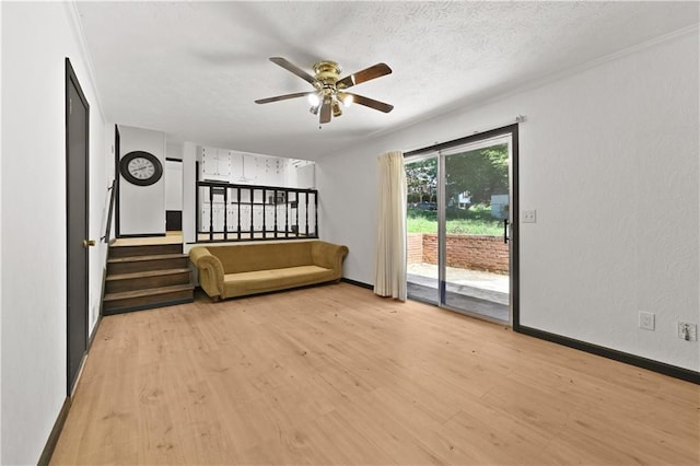 unfurnished living room with baseboards, stairway, a textured ceiling, and light wood-style floors