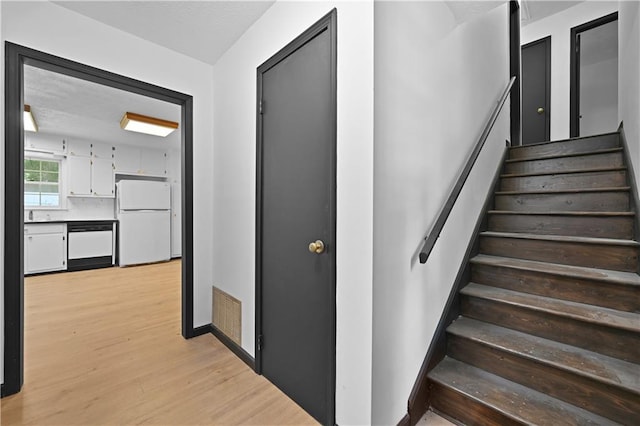 staircase featuring visible vents and wood finished floors