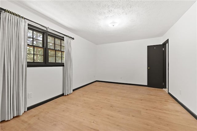 empty room with baseboards, light wood-style flooring, and a textured ceiling