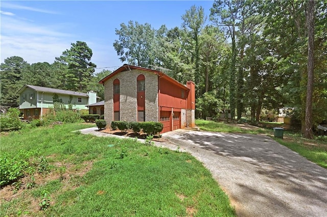 view of side of home featuring driveway, an attached garage, and brick siding