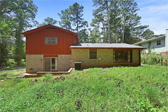 back of property with central air condition unit, board and batten siding, and brick siding