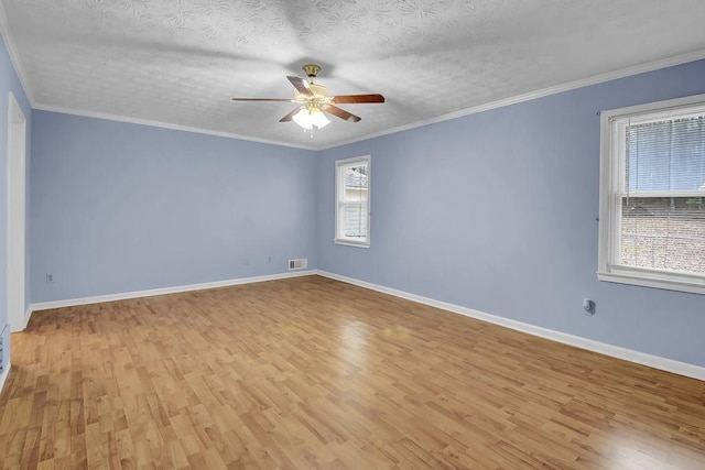 empty room with crown molding, light hardwood / wood-style floors, and a textured ceiling